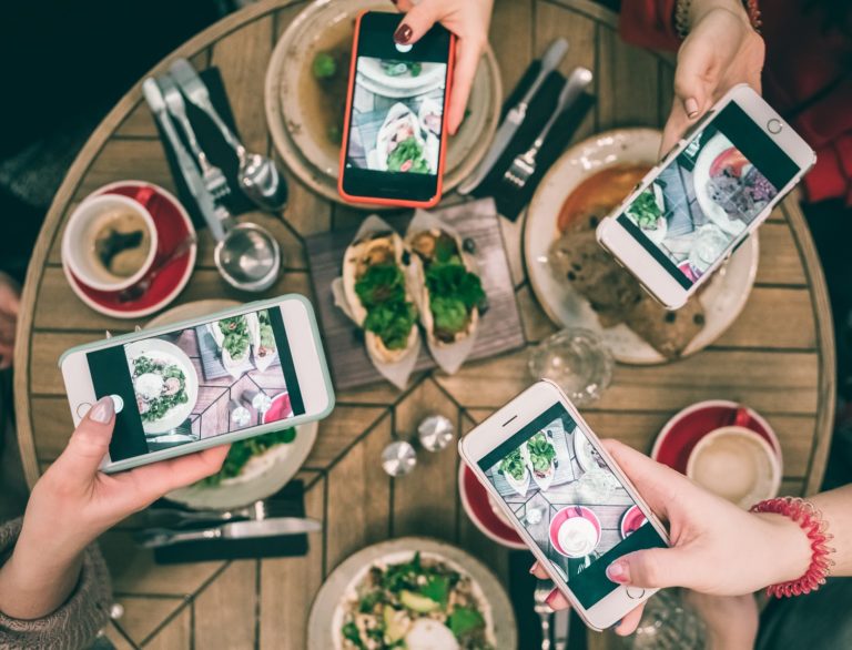 4 customers taking photos of their restaurant meal for social media