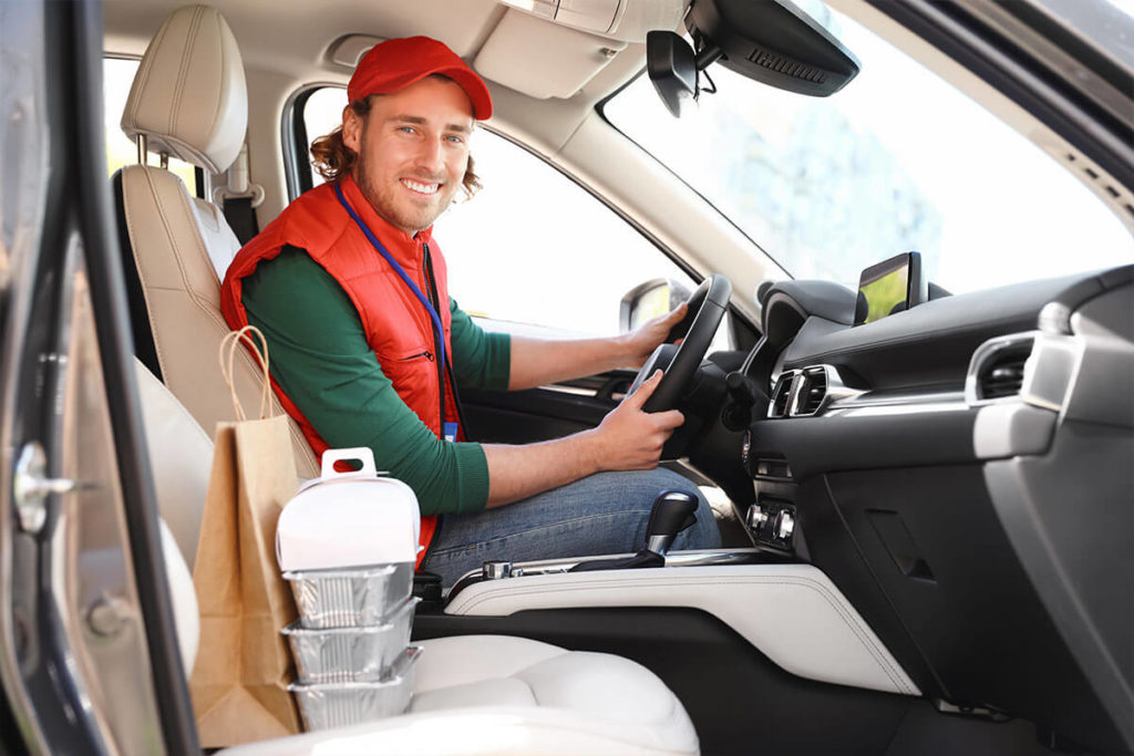 Male food delivery service provider for restaurant in a clean, modern vehicle